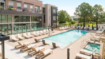 A swimming pool with lounge chairs and a building in the background